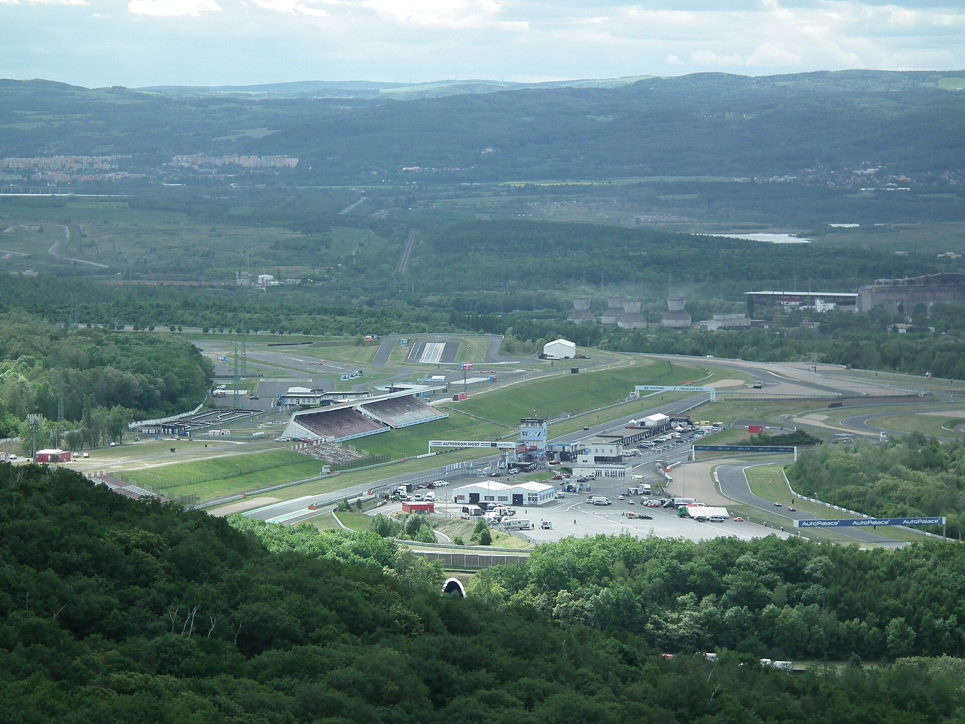 Autodrom Most seen from Hněvín hill: the grandstand, tower and paddock beyond a wooded slope