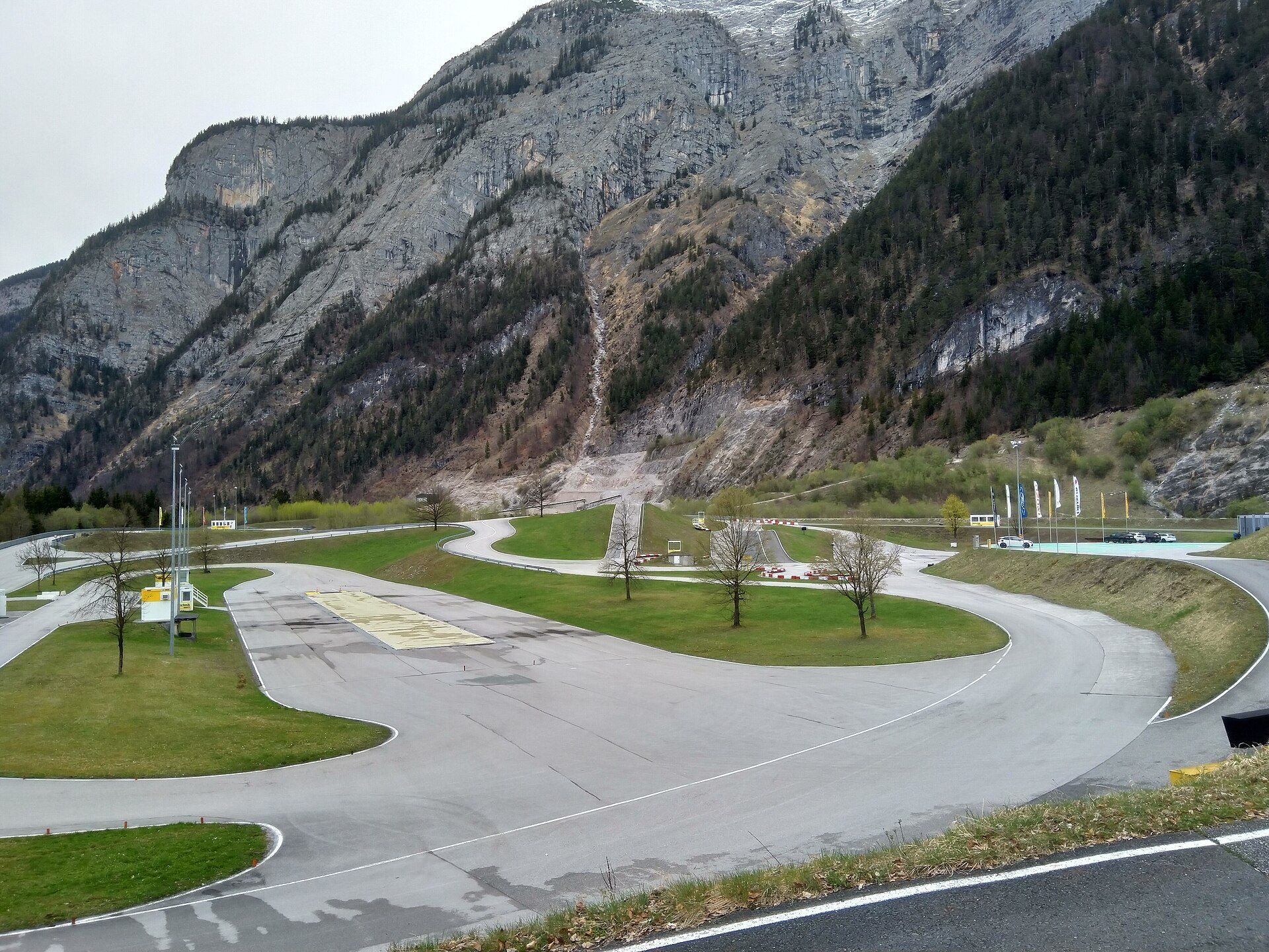 Winding asphalt training tracks of the ÖAMTC Saalfelden/Brandlhof centre between lawns, with steep rocky mountainsides behind